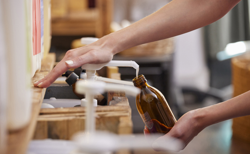 Someone refilling refillable bottle with pump of product